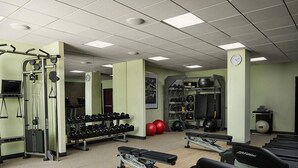 Un gimnasio con cintas de correr, máquinas de pesas y pesas sueltas.