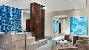 Un lobby moderno con una pared de azulejos azules, una escalera y una zona de estar con una mesa de centro.