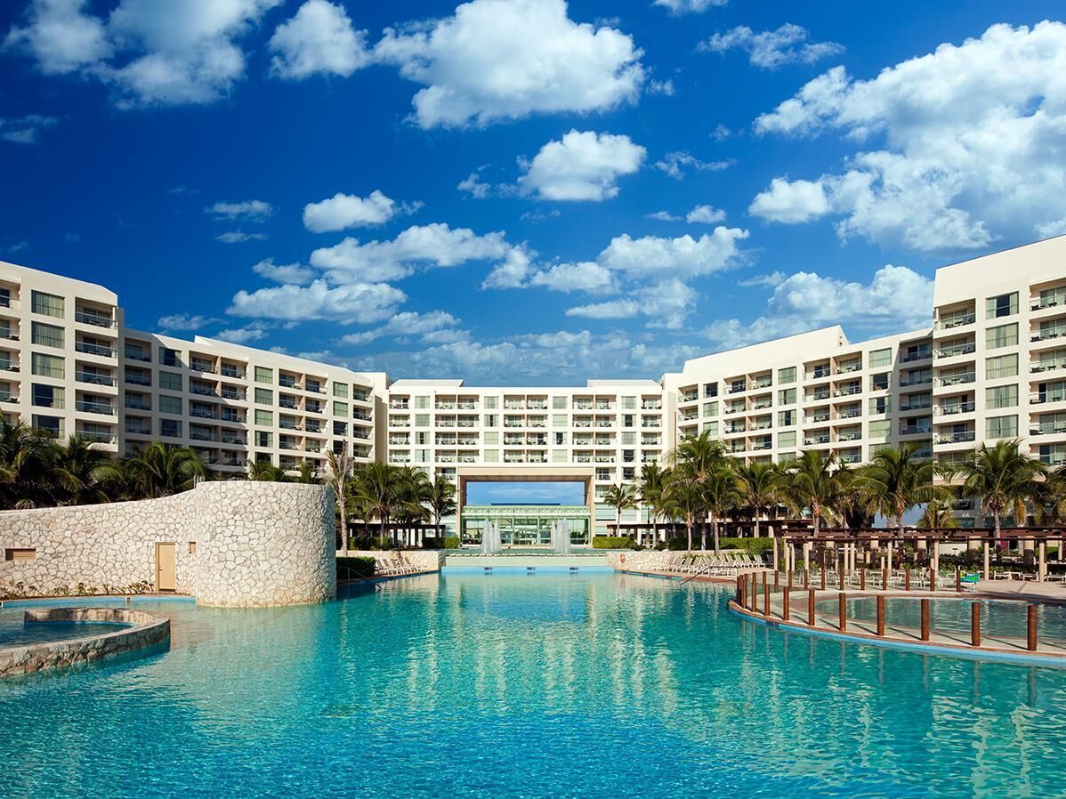 Un resort con piscina central, varios balcones y cielo despejado.
