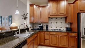 Eine Küche mit Holzausstattung, Granitarbeitsplatten, einem Edelstahlspülbecken und einem eingebauten Backofen.