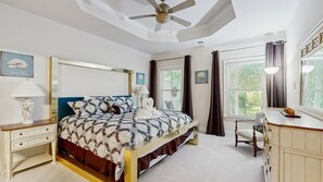 A bedroom with a bed, bedside tables, a desk, a chair, a ceiling fan, and a window with curtains. - Bayside Resort - 36620 Day Lily Pkwy (Selbyville)