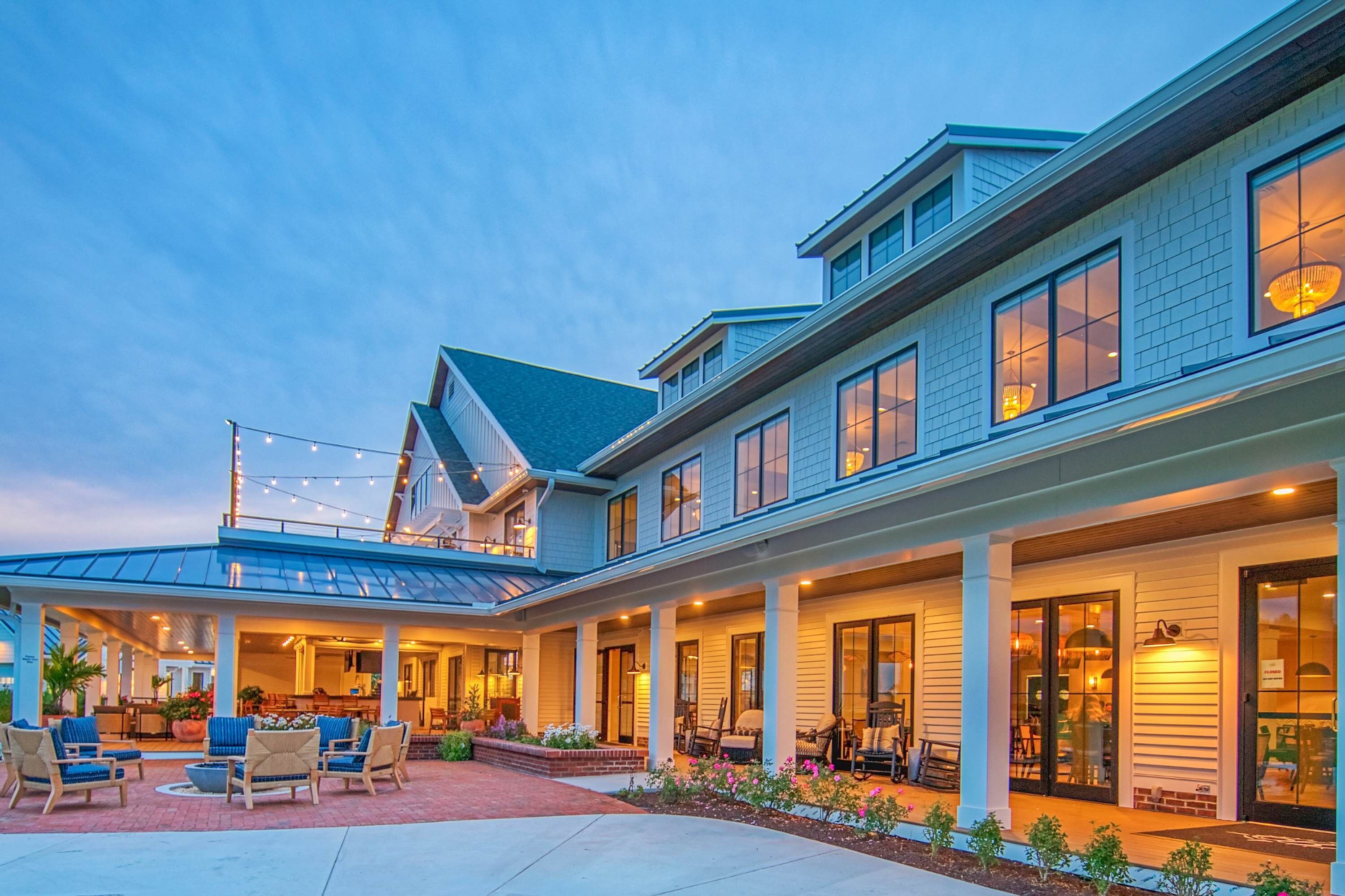 A two-story building with a covered patio area, outdoor seating, and a well-lit entrance.