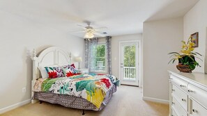 Ein Schlafzimmer mit einem Bett, einem Deckenventilator, einer Kommode und einem Fenster mit Vorhängen.