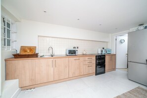 A modern kitchen with wooden cabinets, a microwave, a sink, and a refrigerator. - Welcome to your Stylish home in central London. (London)