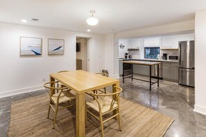 Eine moderne Küche mit Edelstahlgeräten, einem Holzespeisesaal mit Stühlen und Bildern an der Wand.