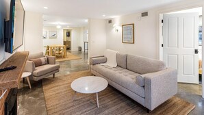 A modern living room with a sofa, coffee table, and a TV on a wooden stand. - Park House Garden - Ground Floor Two-Bedroom Apartment on Monterey Square (Savannah)