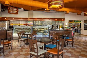 Un restaurante con piso a cuadros, sillas de madera y una barra central con vitrina.