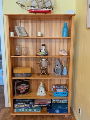 Een houten plank met verschillende gezelschapsspellen, een schipmodel en nautische decoraties.