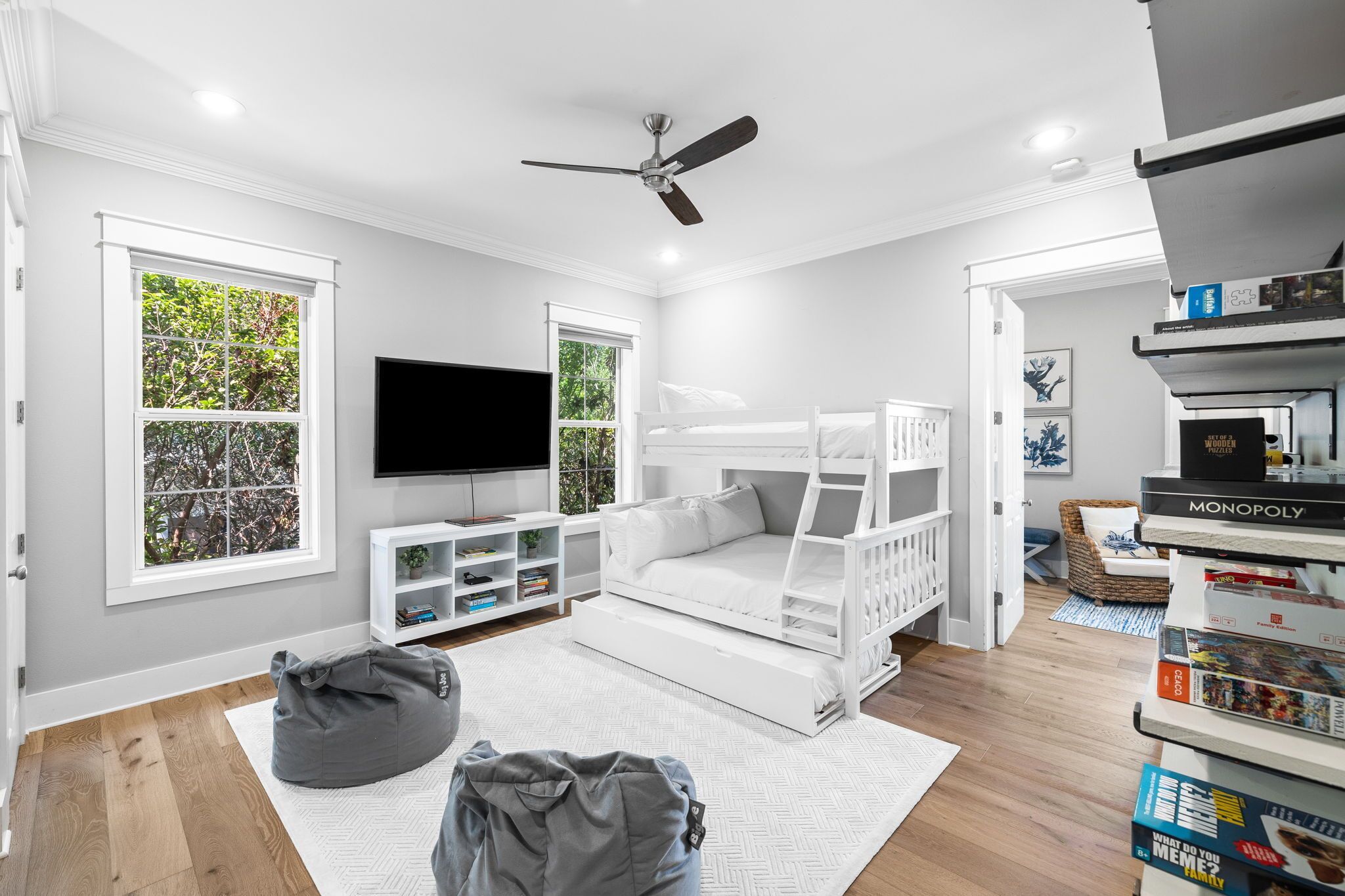 A modern child’s room with a bunk bed, a flat-screen TV, and a bookshelf.