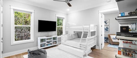 Quarto infantil moderno com cama beliche, televisão de tela plana e estante de livros.