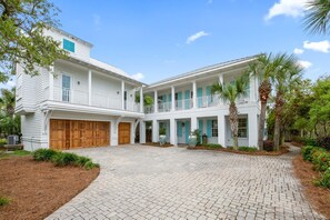 A two-story house with a covered porch, a garage, and a paved driveway. - Professionally Decorated with LSV and Pool (Seacrest Beach)