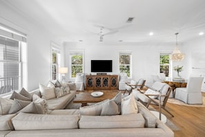 A spacious living room with a large sofa, a wooden coffee table, and a flat-screen TV. - Professionally Decorated with LSV and Pool (Seacrest Beach)