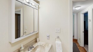 Un baño con tocador, un espejo grande y un perchero para toallas.