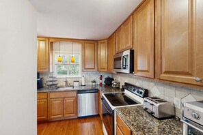 A kitchen with wooden cabinets, a stainless steel dishwasher, a stove, a microwave, and a toaster. - Cozy 3BR Condo- Indoor Pool- Near Ski & Waterpark (Tannersville)