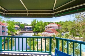 A balcony with a view of a river, buildings, and a pool area. - Lagoon-View Villa - Walk to Shelter Cove (Hilton Head Island)