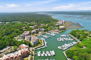 A marina with multiple boats docked, surrounded by residential buildings and lush greenery. - Lagoon-View Villa - Walk to Shelter Cove (Hilton Head Island)