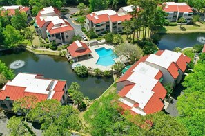 A residential area with multiple buildings, a central swimming pool, and a body of water. - Lagoon-View Villa - Walk to Shelter Cove (Hilton Head Island)