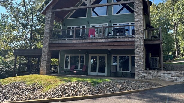 Ein zweistöckiges Lodge-Haus mit Natursteinfassade, großen Fenstern und einem Balkon.
