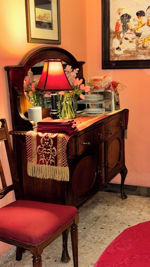 A room with a wooden cabinet, a chair, a table with a red cloth, a lamp, and a painting on the wall. - Serviced, 4 BR House in Chapalita, near Expo (Guadalajara)