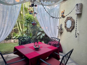 An outdoor patio with a table set for two, surrounded by chairs, and a decorative wall with a mirror and wall-mounted lights. - Serviced, 4 BR House in Chapalita, near Expo (Guadalajara)
