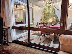 A room with a sliding glass door leading to an outdoor area with a table and chairs, a chair with a cushion, and a sign on the door. - Serviced, 4 BR House in Chapalita, near Expo (Guadalajara)