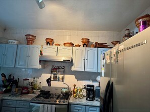 A kitchen with white cabinets, a gas stove, a coffee maker, and a refrigerator. - Serviced, 4 BR House in Chapalita, near Expo (Guadalajara)