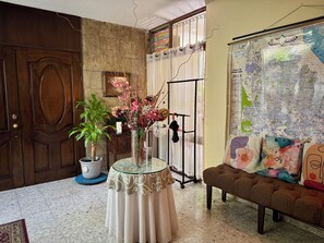 A room with a wooden door, a potted plant, a glass table with a decorative cover, a bench, and a wall map. - Serviced, 4 BR House in Chapalita, near Expo (Guadalajara)