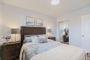 Un dormitorio con una cama grande, dos mesitas de noche, un aparador y un espejo.