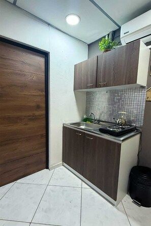 A compact kitchen with a tiled backsplash, a built-in stove, and a small sink.