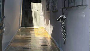 A narrow alleyway with a tiled floor leading to a gated entrance.