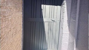 A dark-colored door with a handle, a welcome mat, and a security camera above it.