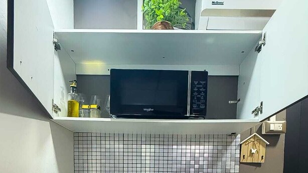 A compact kitchen with a microwave, sink, and kettle.