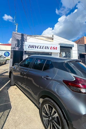 A car parked in front of a building with a sign that reads 'DRYCLEAN USA'.