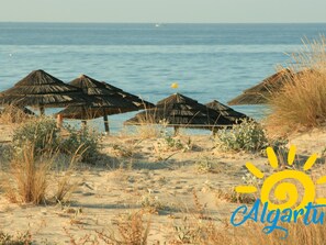 A beach with thatched umbrellas and a clear view of the sea. - Quinta Gomeira - Top Floor 2 Bedroom with pool (Cabanas de Tavira)