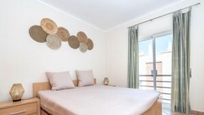 Ein modernes Schlafzimmer mit einem großen Bett, einem Nachttisch mit Lampe und einem Wanddekor.
