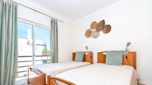 Ein Zimmer mit zwei Holzbetten, einer Schiebeglasdoor und Blick ins Freie.