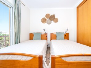 Ein Doppelzimmer mit hölzernen Kopfteilen, Blick ins Freie und einer Wanddekoration.
