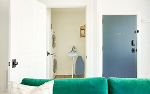 A room with a green sofa, a washing machine, and a blue door. - Park House Parlor Level - 2 Bedroom/2 Bath Overlooking Monterey Square (Savannah)