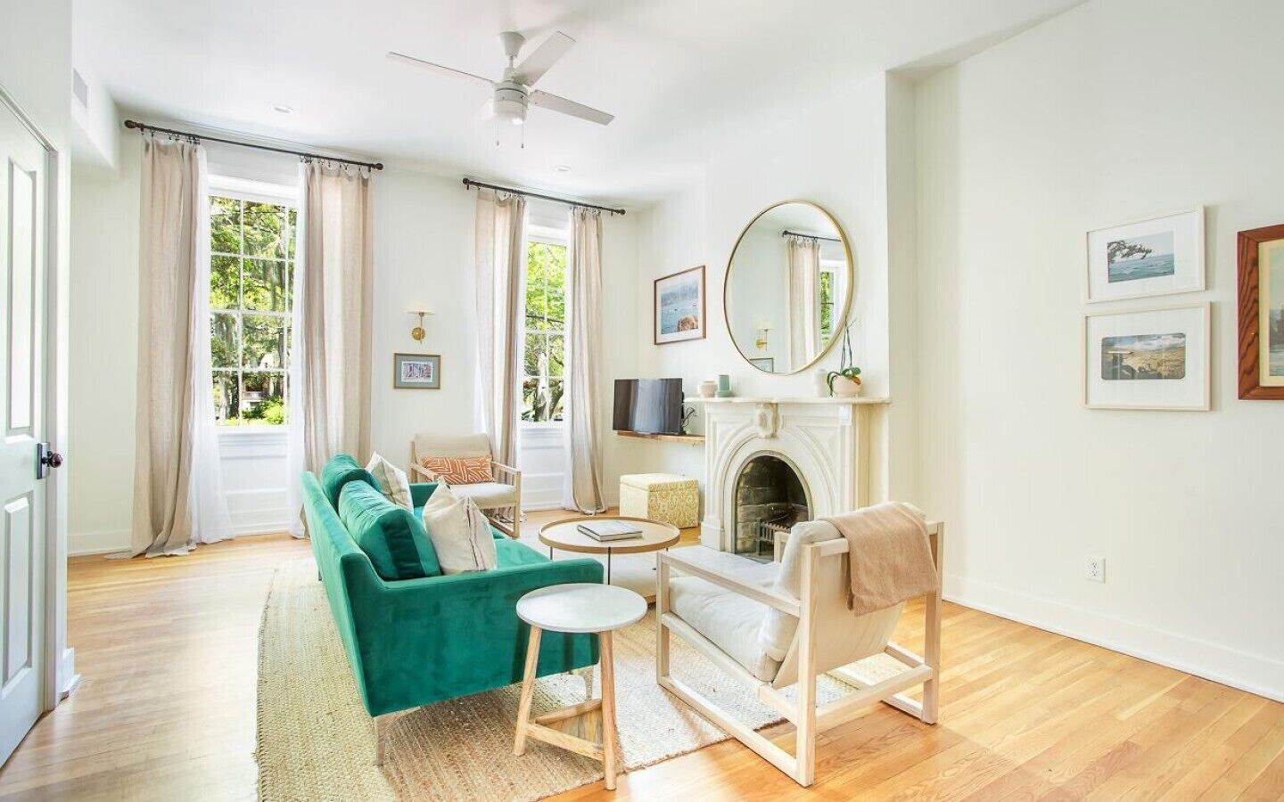 Een zithoek met een bank, fauteuil, open haard, televisie en kunst aan de muur.