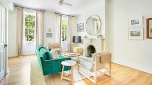 Ein Wohnzimmer mit Sofa, Sessel, Kamin, Fernseher und Kunstwerken an der Wand.
