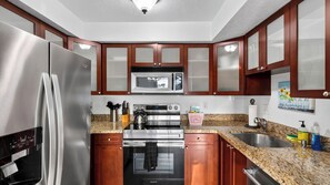 A modern kitchen with stainless steel appliances, wooden cabinets, granite countertops, and a stainless steel sink.