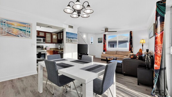 A modern living space with a dining area, kitchen, and seating area.