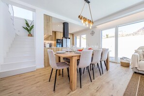 Ein Essbereich mit Holztisch und -stühlen, eine Treppe und eine Küche im Hintergrund.