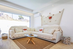Un salón moderno con un sofá blanco, una mesa de centro de cristal y un ventanal grande.
