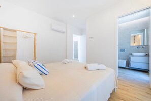 Een hotelkamer met een bed, een nachtkastje, een handdoekrek en een zichtbare badkamer door een open deur.