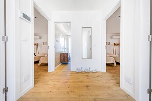 Ein Hotelgang mit Holzboden, weißen Wänden und Türen zu den Schlafzimmern.