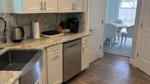 A kitchen with white cabinets, a stainless steel dishwasher, and a coffee maker. - Welcome to our beautiful 3-bedroom, 2-bath home in the heart of Marco Island! (Marco Island)