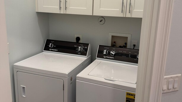 A laundry room with two white front-loading washing machines and cabinets above. - Welcome to our beautiful 3-bedroom, 2-bath home in the heart of Marco Island! (Marco Island)