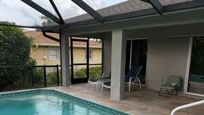 A covered swimming pool with lounge chairs and a clear view of the backyard. - Welcome to our beautiful 3-bedroom, 2-bath home in the heart of Marco Island! (Marco Island)