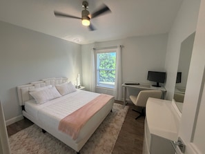 A bedroom with a bed, a desk, a chair, a ceiling fan, and a window. - Welcome to our beautiful 3-bedroom, 2-bath home in the heart of Marco Island! (Marco Island)